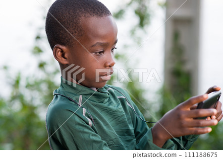 Child playing on the phone outdoors in sunny day Child playing on the phone outdoors in sunny day 111188675