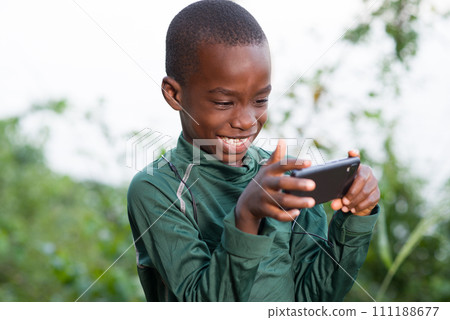 Happy child playing on the phone outdoors in sunny day Happy child playing on the phone outdoors in sunny day 111188677