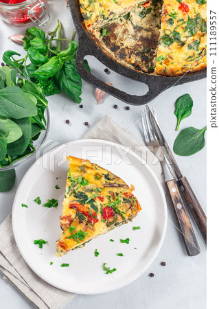 Piece of brunch egg frittata with vegetables on plate, vertical, top view Piece of brunch egg frittata with vegetables on plate, vertical, top view 111189557