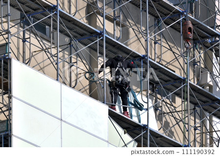 Large-scale demolition work: A steeplejack worker installing soundproof panels on temporary scaffolding Large-scale demolition work: A steeplejack worker installing soundproof panels on temporary scaffolding 111190392