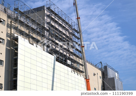 Large-scale demolition work: A steeplejack worker installing soundproof panels on temporary scaffolding Large-scale demolition work: A steeplejack worker installing soundproof panels on temporary scaffolding 111190399