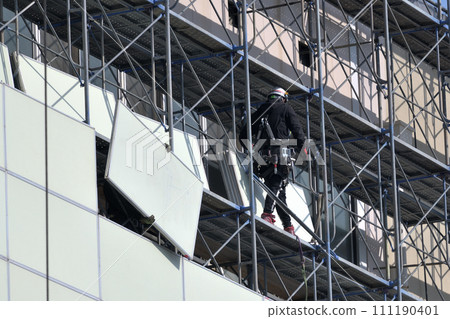 Large-scale demolition work: A steeplejack worker installing soundproof panels on temporary scaffolding 111190401
