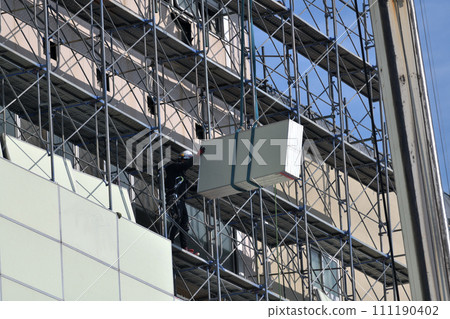 Large-scale demolition work: A steeplejack worker installing soundproof panels on temporary scaffolding 111190402