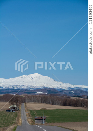Spring hilly upland field and mountain range of remaining snow Daisetsuzan Spring hilly upland field and mountain range of remaining snow Daisetsuzan 111193492
