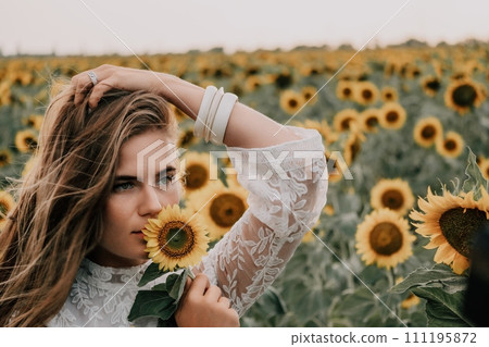 Woman in Sunflower Field: Happy girl in a straw hat posing in a vast field of sunflowers at sunset, enjoy taking picture outdoors for memories. Summer time. 111195872