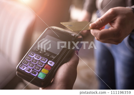 NFC credit card payment. Woman paying with contactless credit card with NFC technology. Wireless money transaction. Card machine in male hand on sunlight background NFC credit card payment. Woman paying with contactless credit card with NFC technology. Wireless money transaction. Card machine in male hand on sunlight background 111196359