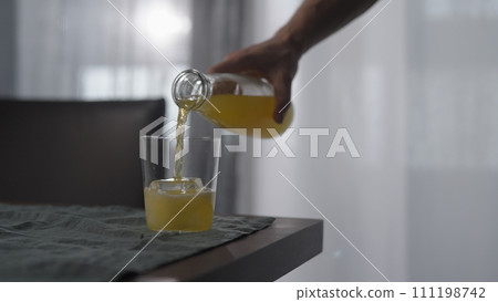 man pour lemonade in tumbler glass with ice cube on wood table man pour lemonade in tumbler glass with ice cube on wood table 111198742