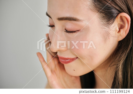 A woman in her 30s with long hair applying foundation 111199124