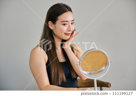A woman in her 30s with long hair applying foundation 111199127