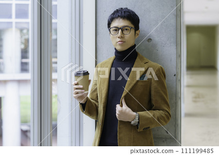 Portrait of a young man wearing glasses and standing with a drink cup Photography cooperation: Ariake College of Education and Art 111199485