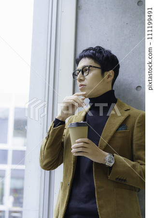 Portrait of a young man wearing glasses and standing with a drink cup, vertical position. Photography cooperation: Ariake College of Education and Art 111199491