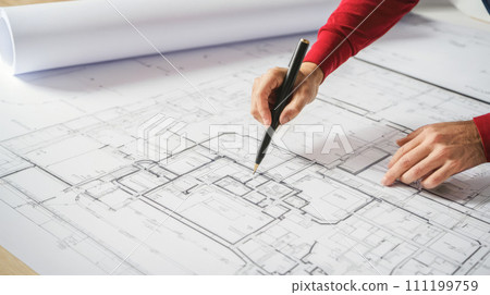 Home Remodeling Blueprint Review. Professional reviewing and making changes to detailed architectural plan for home remodeling, focusing on layout adjustments and design improvements 111199759