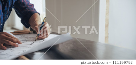 Architectural Revision Process: Close-up of expert altering residential blueprint, highlighting meticulous process of enhancing and optimizing living spaces. 111199792