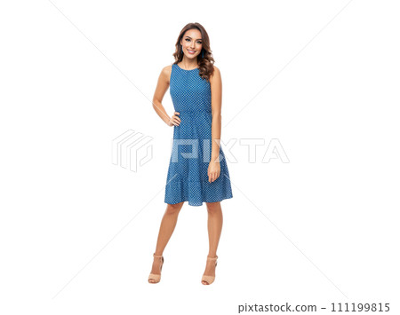 Young woman in stylish blue dress with white polka dots, isolated on white background. stands confidently, hand on hip, showcasing fashion and elegance. advertising modern, trendy female clothing 111199815