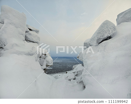 Dangerous winter gorge, a cliff between two snow rocks. Dangerous winter gorge, a cliff between two snow rocks. 111199942