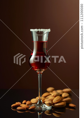 Italian liqueur Amaretto with almonds nuts on a brown background. Italian liqueur Amaretto with almonds nuts on a brown background. 111200080