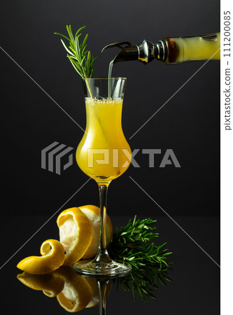 Traditional Italian liqueur Limoncello with rosemary twig on a black reflective background. Traditional Italian liqueur Limoncello with rosemary twig on a black reflective background. 111200085