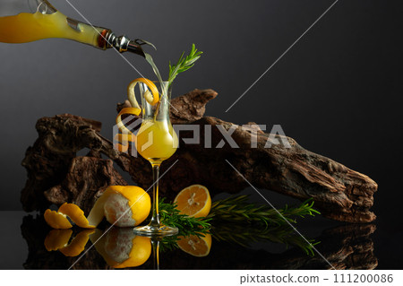 Traditional Italian liqueur Limoncello on a black reflective background. Traditional Italian liqueur Limoncello on a black reflective background. 111200086