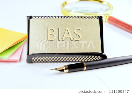 Bias text on a gold plastic card with convex text next to office supplies on a white background 111200347
