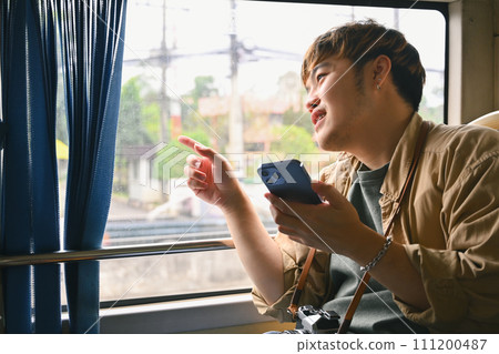 Happy tourist man looking through the window while commuting by bus 111200487