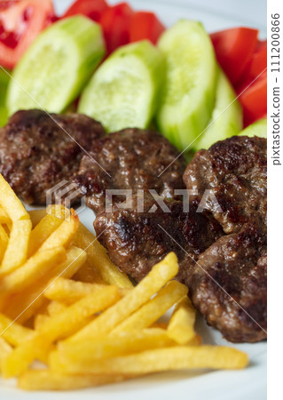 Traditional Turkish meatballs served with French fries tomatoes . High quality photo Traditional Turkish meatballs served with French fries tomatoes . High quality photo 111200866