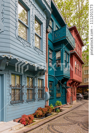 Vibrant scene in Istanbul's Uskudar district: colorful wooden houses line the cobblestone path, bursting with charm Vibrant scene in Istanbul's Uskudar district: colorful wooden houses line the cobblestone path, bursting with charm 111201573