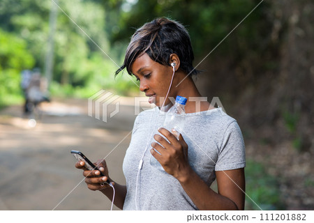 Young woman in sportswear listening to music in headphones Young woman in sportswear listening to music in headphones 111201882