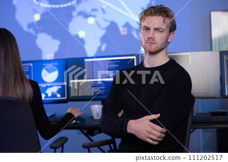 Serious Male Cybersecurity Analyst in large Cyber Security Operation Center SOC handling Threats Serious Male Cybersecurity Analyst in large Cyber Security Operation Center SOC handling Threats 111202517