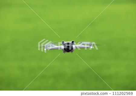 Flying drone quadcopter with a camera on green background. 111202569