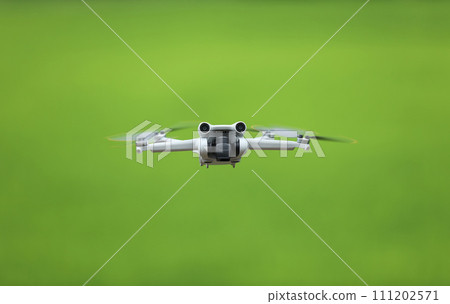 Flying drone quadcopter with a camera on green background. Flying drone quadcopter with a camera on green background. 111202571