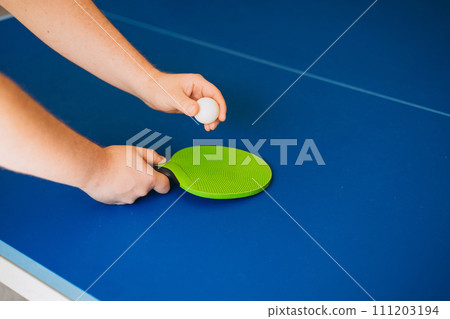 A man is playing ping pong. He holds a white ball and a green racket in his hands. Table tennis. The concept of sport and healthy lifestyle. A man is playing ping pong. He holds a white ball and a green racket in his hands. Table tennis. The concept of sport and healthy lifestyle. 111203194