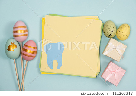 Greeting card for dentistry happy easter, space for text in center, tooth with painted eggs and gifts top view 111203318