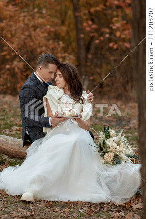 bride and groom on the nature in autumn . wedding couple with cake outdoor 111203702