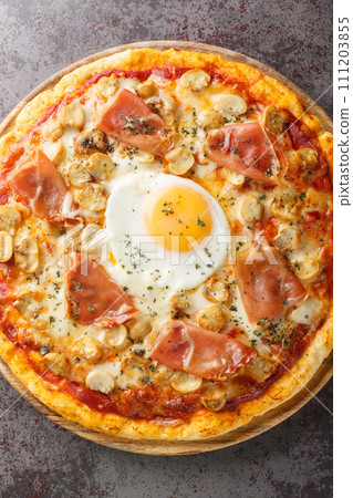 Traditional Pizza Bismarck made of egg, mozzarella, tomato, mushrooms and prosciutto closeup on the wooden board. Vertical top view 111203855