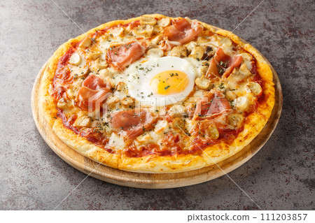 Pizza Bismarck is a style of pizza in Italian cuisine prepared with tomato sauce, mozzarella, mushrooms, prosciutto, and egg closeup on the wooden board. Horizontal 111203857
