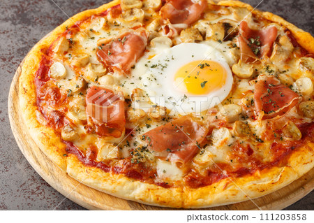 Bismark is the name of a traditional Italian pizza topped with tomato sauce, mozzarella, prosciutto, and egg closeup on the wooden board. Horizontal 111203858