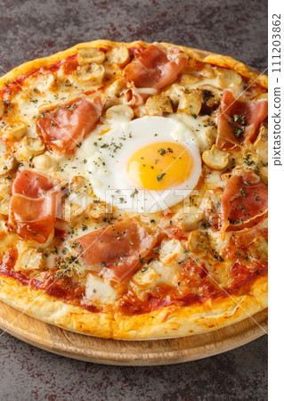 Traditional Pizza Bismarck made of egg, mozzarella, tomato, mushrooms and prosciutto closeup on the wooden board. Vertical 111203862
