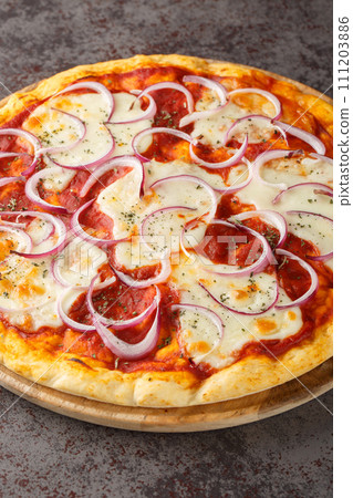 Pizza pugliese is a style of pizza in Italian cuisine prepared with tomato, onion, and mozzarella closeup on the wooden board. Vertical 111203886