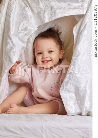 cute funny baby girl hiding under blanket on the bed cute funny baby girl hiding under blanket on the bed 111203975