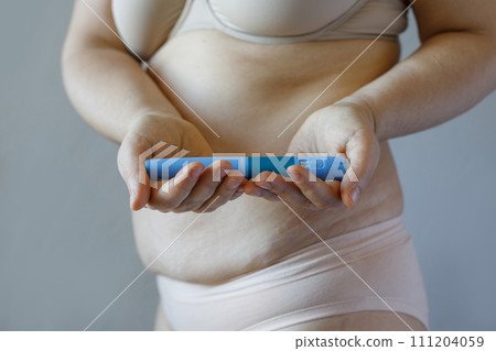 Blue Semaglutide Injection pen closeup. Semaglutide or insulin drug against female model belly 111204059