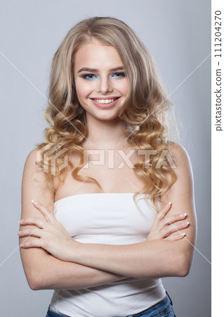 Smiling young woman with clean fresh skin and long curly hair looking at camera 111204270