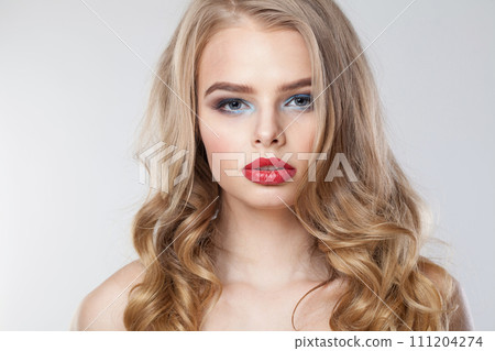 Fashionable young woman with clean fresh skin and long curly hair looking at camera Fashionable young woman with clean fresh skin and long curly hair looking at camera 111204274