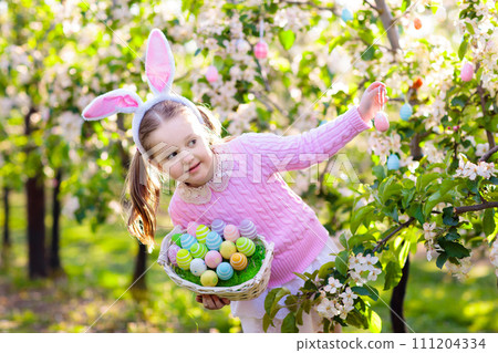 Child with bunny ears on garden Easter egg hunt Child with bunny ears on garden Easter egg hunt 111204334