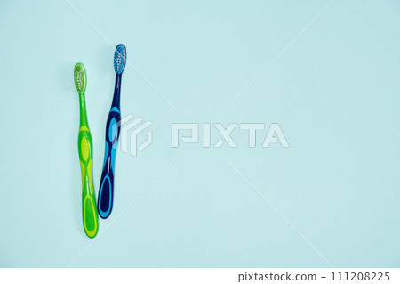 Two toothbrushes on a blue background, top view, space for text. 111208225