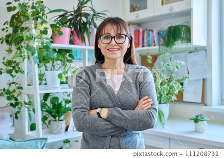 Portrait of confident smiling middle-aged woman with crossed arms at home Portrait of confident smiling middle-aged woman with crossed arms at home 111208731