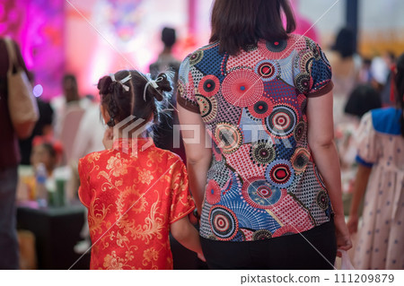 mom holding hand of girl with red China qipao cheongsam dress to celebrate 2024 dragon Chinese year mom holding hand of girl with red China qipao cheongsam dress to celebrate 2024 dragon Chinese year 111209879