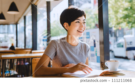 beautiful Asian woman with short pixie haircut in casual tee looking at the menu in a cafe, 16:9 widescreen image 111211068