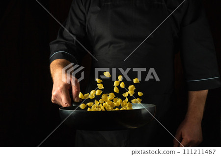 The cook prepares a healthy breakfast of pasta in a frying pan. Healthy vegetarian food and dishes recipe. Place on a dark background for the recipe The cook prepares a healthy breakfast of pasta in a frying pan. Healthy vegetarian food and dishes recipe. Place on a dark background for the recipe 111211467