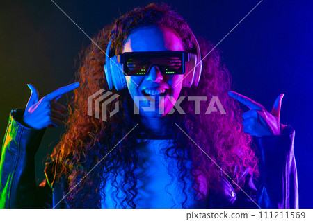 Positive woman listening music, enjoying with headphones, neon studio Positive woman listening music, enjoying with headphones, neon studio 111211569