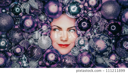 Happy woman face lights up with joy in violet Christmas tree toys balls. Holiday Happy woman face lights up with joy in violet Christmas tree toys balls. Holiday 111211899